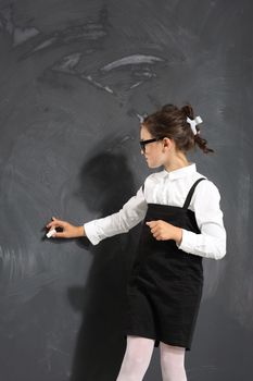 Cute little girl standing by a black school board