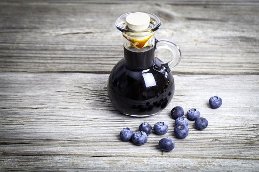 blueberry syrup in glass bottle or mixture, on wooden background.