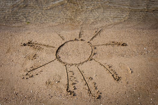 drawing of a sun on sandy beach with water