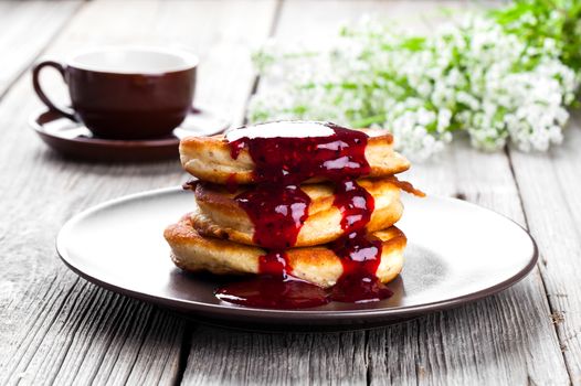 Delicious pancakes with raspberries sauce on the wooden kitchen table