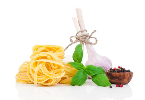 Italian pasta fettuccine nest with garlic and fresh basil leaves, isolated on white background
