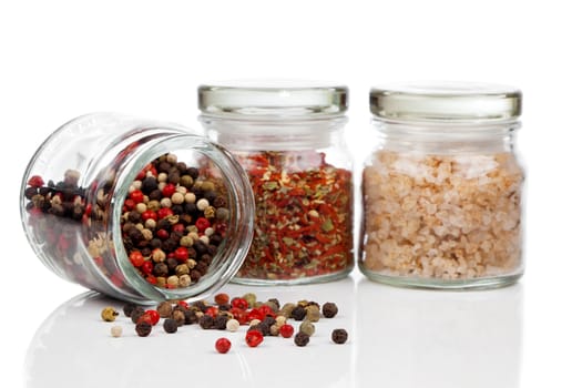 Glass jar with Colored Peppers Mix, red chili pepper and salt, on white background