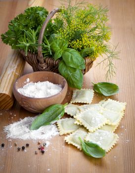 Homemade pasta ravioli with fresh basil, on wooden background