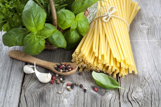 Spaghetti with garlic, peppers, and fresh basil leaves on wooden table