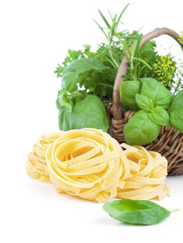 Italian pasta fettuccine nest with fresh basil leaves, on white background