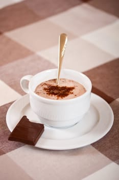 Mug with hot chocolate and a chocolate piece