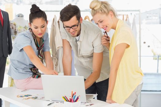 Three fashion designers using laptop in a studio