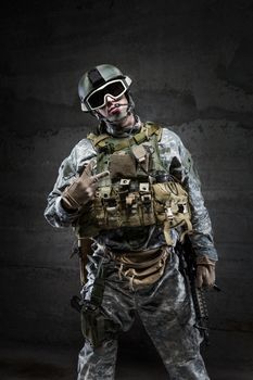 American Soldier in victory gesture on dark background