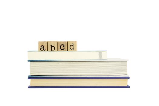 abcd word on wood stamps stack on books, alphabet and english language concepts