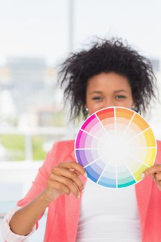Portrait of a beautiful young woman holding color wheel at bright office