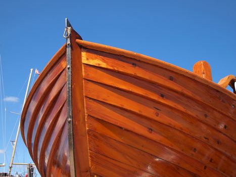 Prow of a small wooden boat with clear blue sky background      