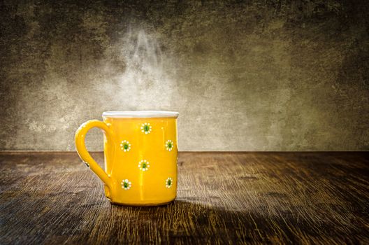 Detail of colorful steaming coffee mug on the table in vintage filtered style