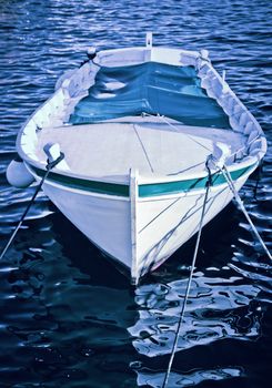 A small Mediterranean wooden fishing boat anchored in the bay