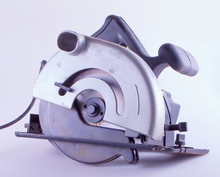 Old and used circular saw over lite gray background