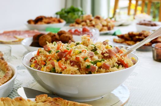 Bowl of gammon and mixed vegetable rice salad with other party food on a buffet table