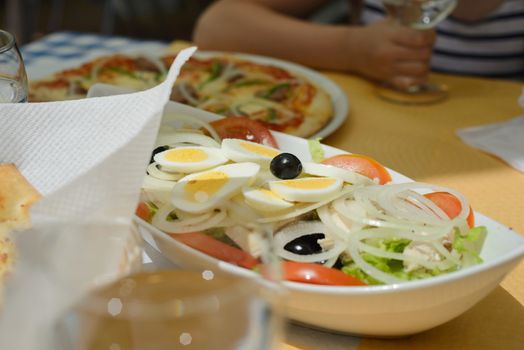Fresh salad with eggs, black olives, onion on the table