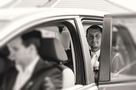 groom sitting in a car, monochrome toned photo
