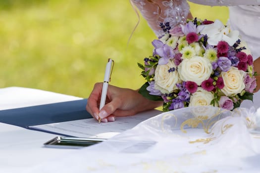 bride with wedding flower signed wedding contract against green grass outdoor