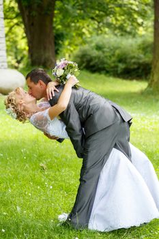 beautiful young wedding couple, groom kissing his blonde bride outdoor
