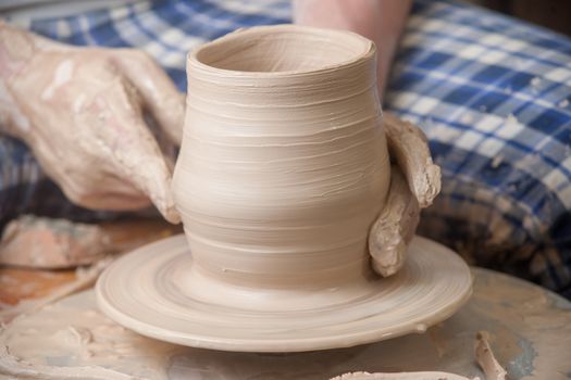 Hands of a potter, creating an earthen jar on the circle