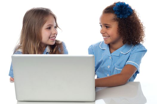 Smiling school girls using laptop together