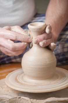 Hands of a potter, creating an earthen jar on the circle