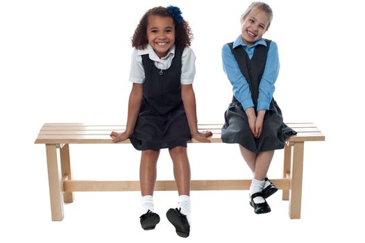 Two cute girls laughing sitting on a bench