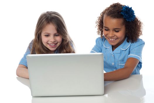 Smiling school girls using laptop together