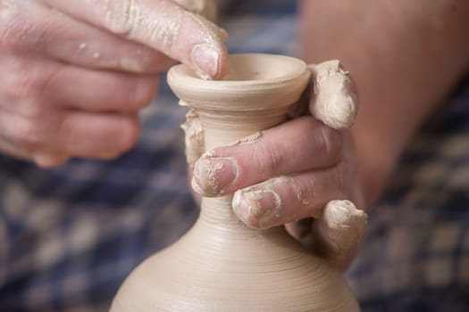 Hands of a potter, creating an earthen jar on the circle