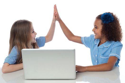 School girls giving high five with laptop