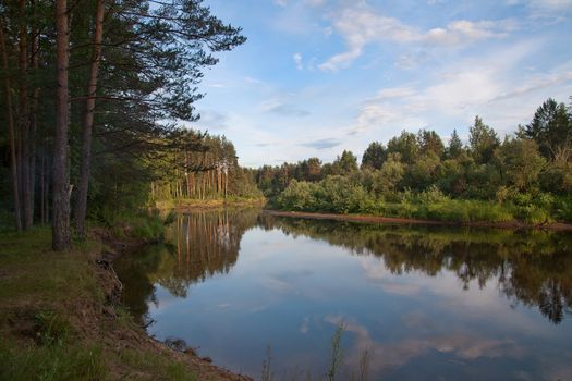 Landscape with river, forest and clouds in the evening