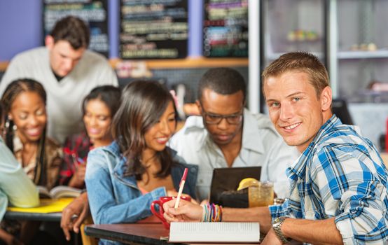 Handsome male student with friends in coffee house