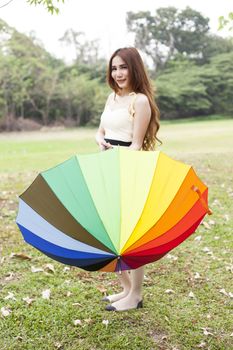 woman standing holding an umbrella On the grass in the park.