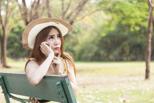 Woman talking on the phone Sitting on a bench in the park.