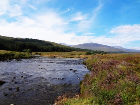 Scottish Highlands river in the mountains with blue sky