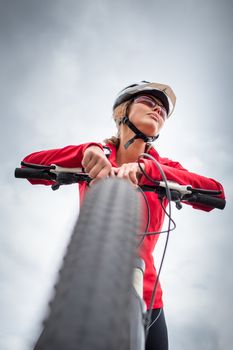 Pretty, young female biker outdoors on her mountain bike (shallow DOF; selective focus)