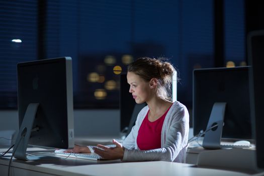 Pretty, young female college student using a desktop computer/pc in a college library (shallow DOF; color toned image)