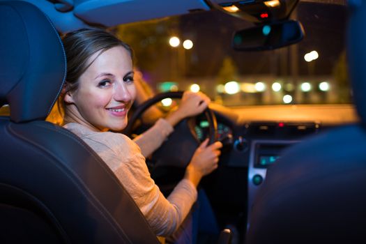 Pretty young woman driving her new car at night