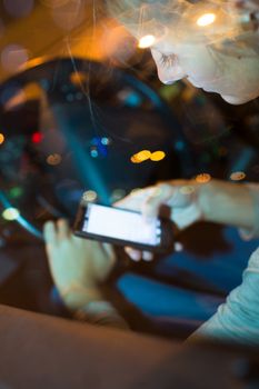 Pretty young woman using her smart phone while driving her car at night