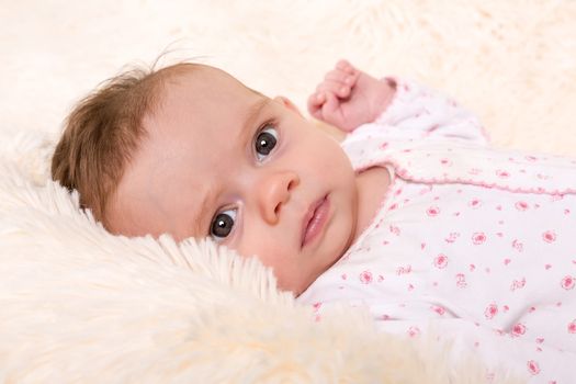 Portrait of Beautiful Baby Girl resting on Cream Fur Rug