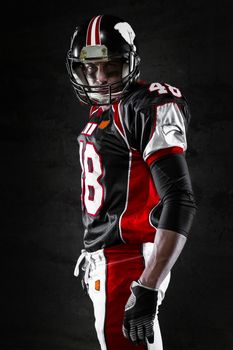 Side view of american football player on dark background