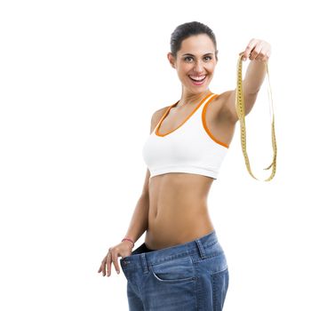 Woman with large jeans in dieting concept holding a measuring tape