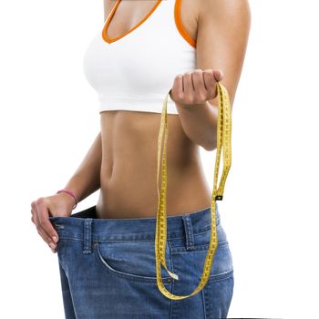 Woman with large jeans in dieting concept holding a measuring tape