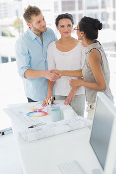 Interior designer shaking hands with happy client in her studio