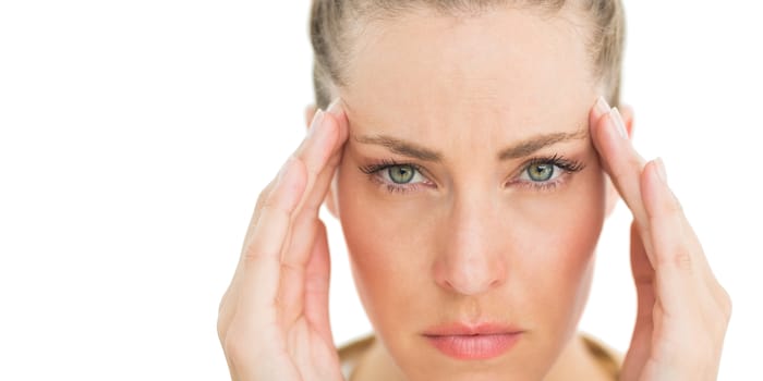 Woman with headache touching her temples frowning at camera on white background