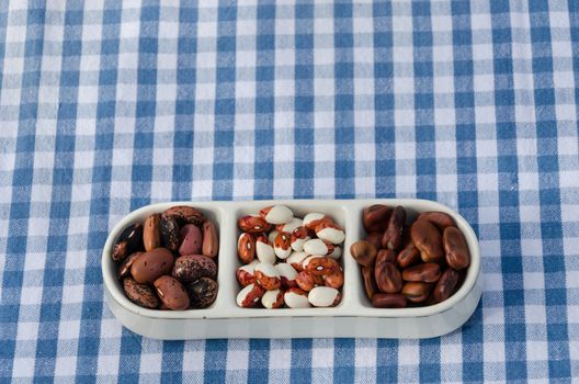 close up of beans mix on three pieces plate on plaid tablecloth background