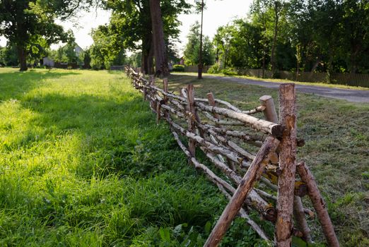 antique rustic rural style twisted fence of thin branches along the road
