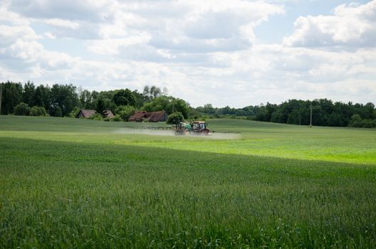 Agriculture tractor with chemical treatment spraying pesticide insecticide on cultivated field.