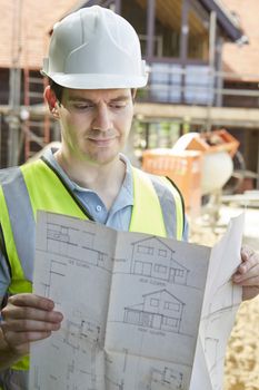Construction Worker On Building Site Looking At House Plans
