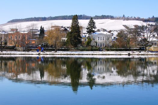 Bernkastel Kues in winter, trees and houses are reflected in the calm waters of the Moselle